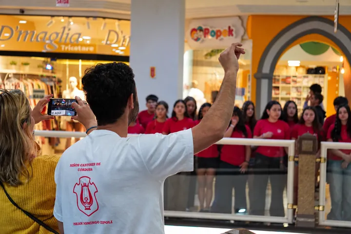 El director guía al coro durante una presentación en un centro comercial.