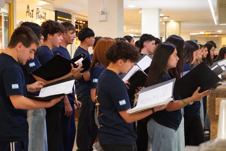 The choir sings with its scores at the shopping centre.
